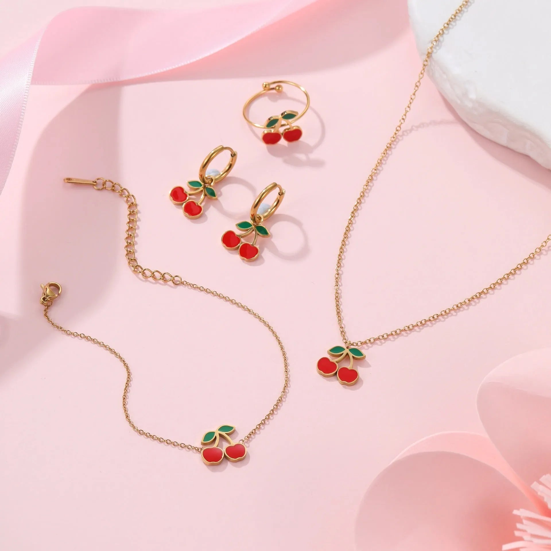 Stainless steel cherry jewellery set showing necklace, bracelet, earrings, and ring with geometric design.