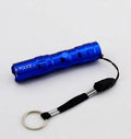 Black aluminium mini LED flashlight showing compact size next to a AA battery for scale.