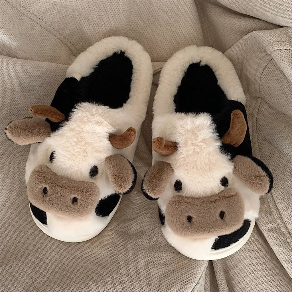 White plush cow slippers for women with black spots, a smiling face, and a textured non-slip sole.