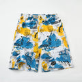Man wearing floral print swimming trunks at the beach, showing the loose fit and colourful pattern.
