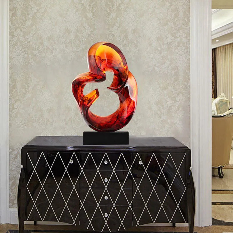 Clear transparent resin sculpture ornament in modern style on a shelf, shown in blue and orange red colour options.