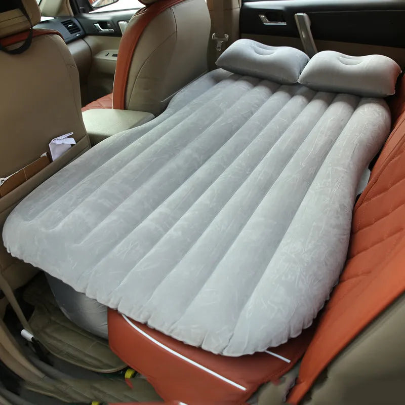 Black inflatable car bed with flocked texture, shown with two pillows inside a car.