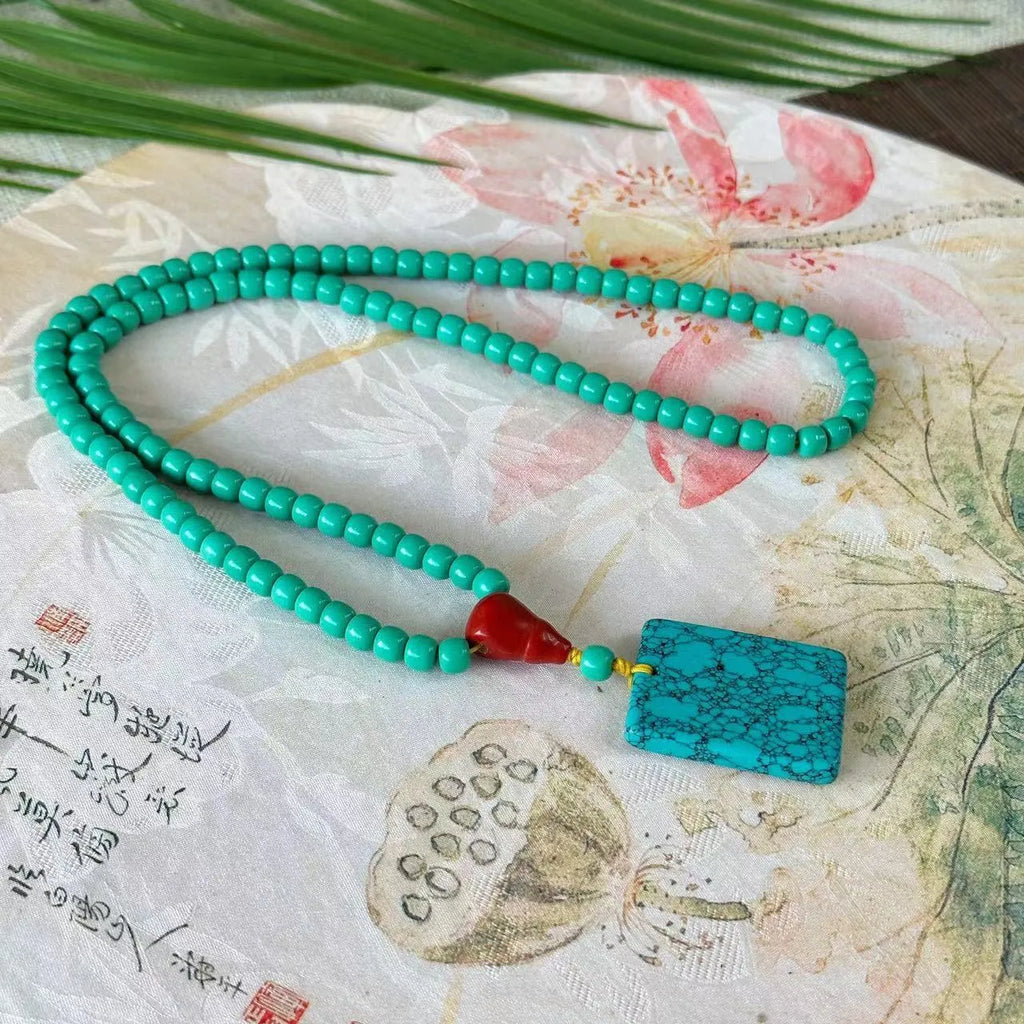 Turquoise mesh flower lucky pendant necklace on a ball bead chain, showing hand-woven detail.