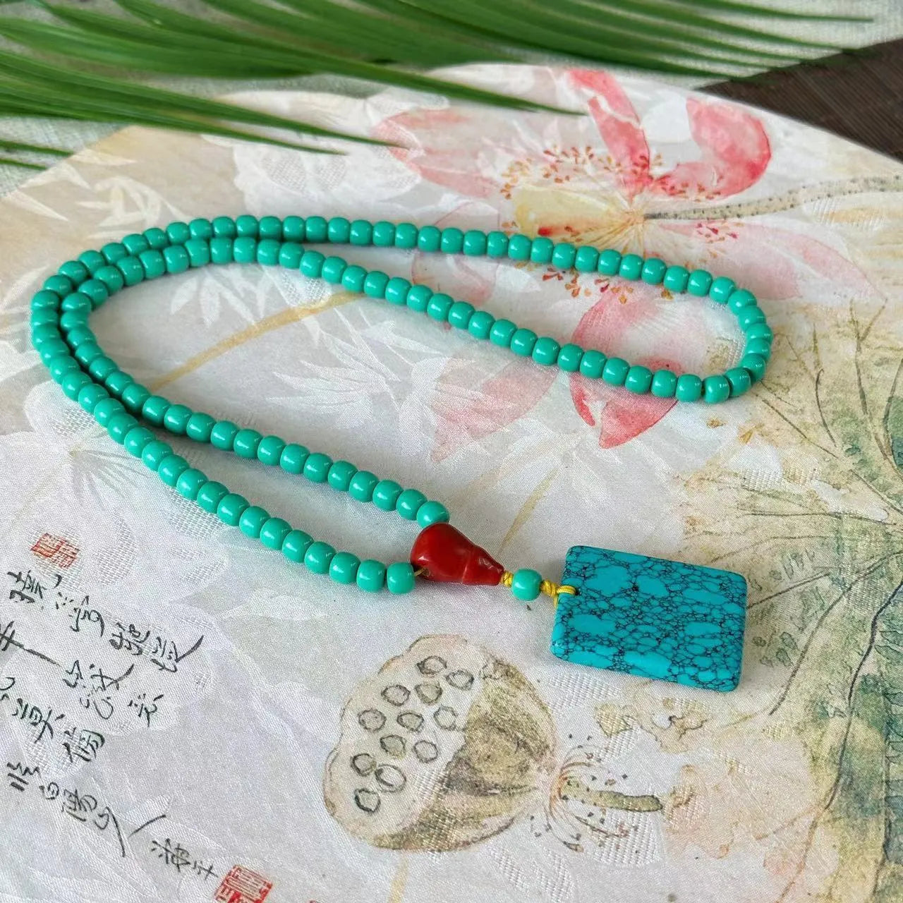 Turquoise mesh flower lucky pendant necklace on a ball bead chain, showing hand-woven detail.