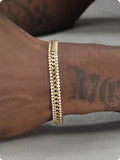 Gold plated tennis bracelet for men and women with stone inlay on a wrist.
