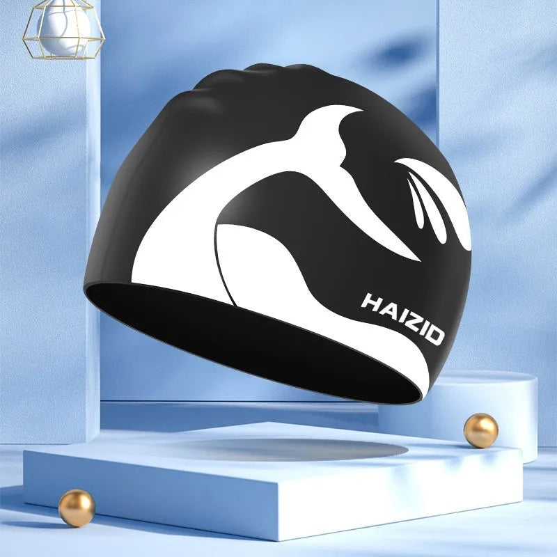 Silicone swim cap with whale tail pattern and built-in ear protectors in assorted colours.