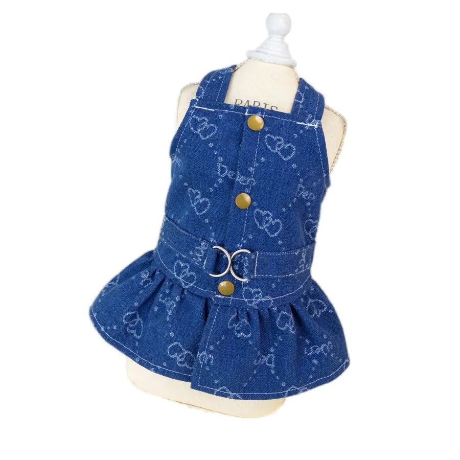 Small white dog wearing a light blue denim bracket-skirt princess dress.