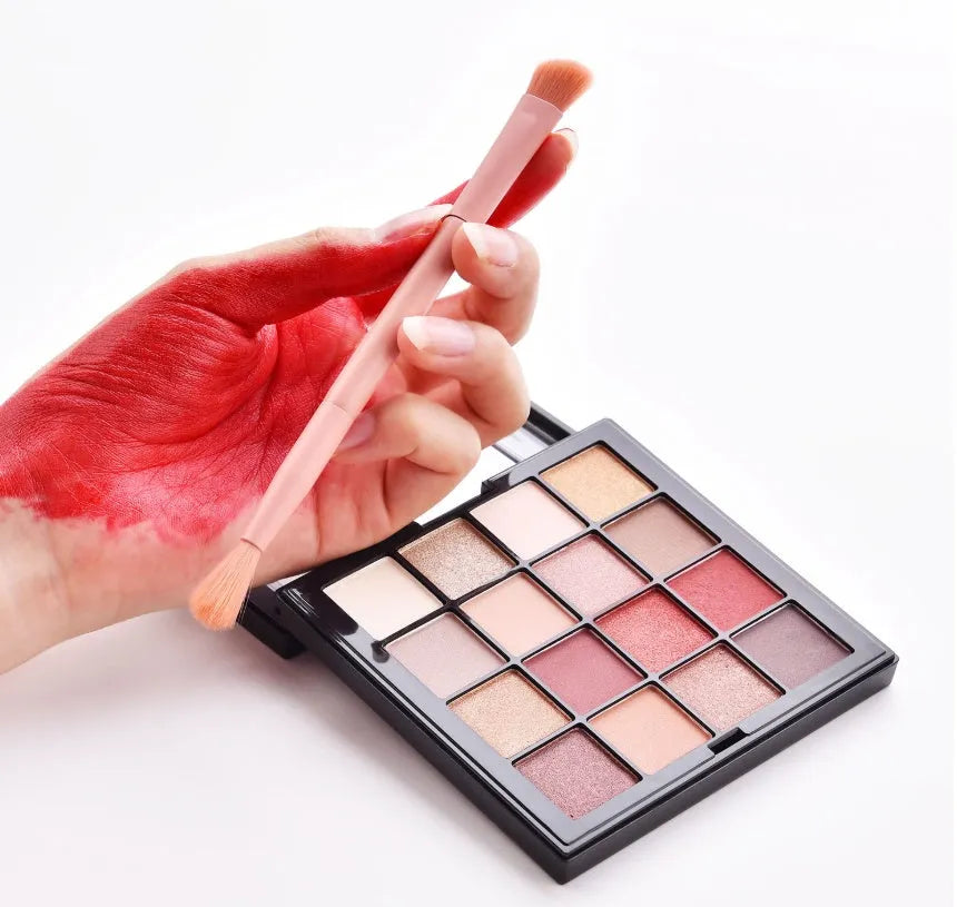 Ten wooden-handle make-up brushes for face and eye application in a pink travel case.