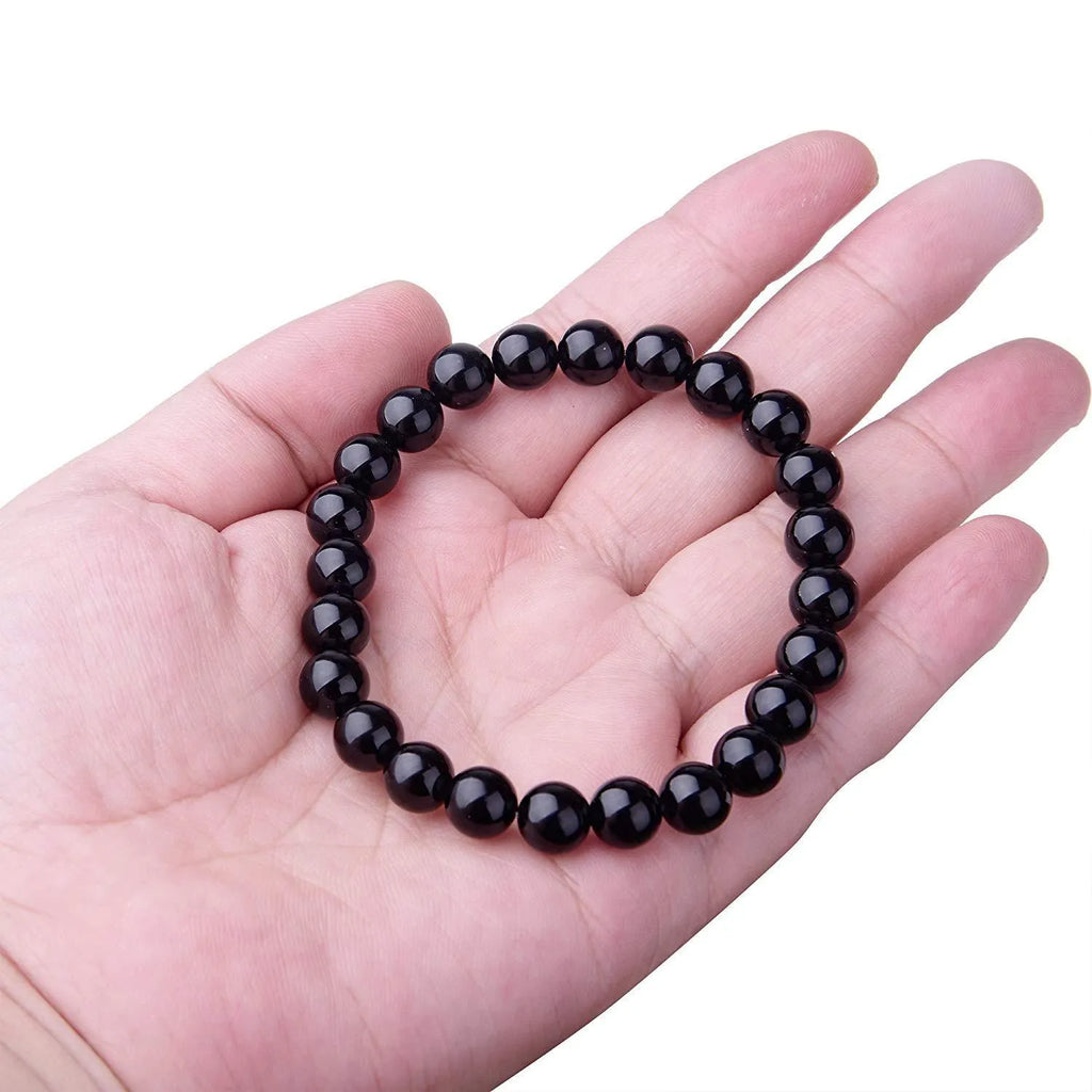 Close-up of a women's black onyx bracelet with 8mm geometric agate beads on a black elastic cord.