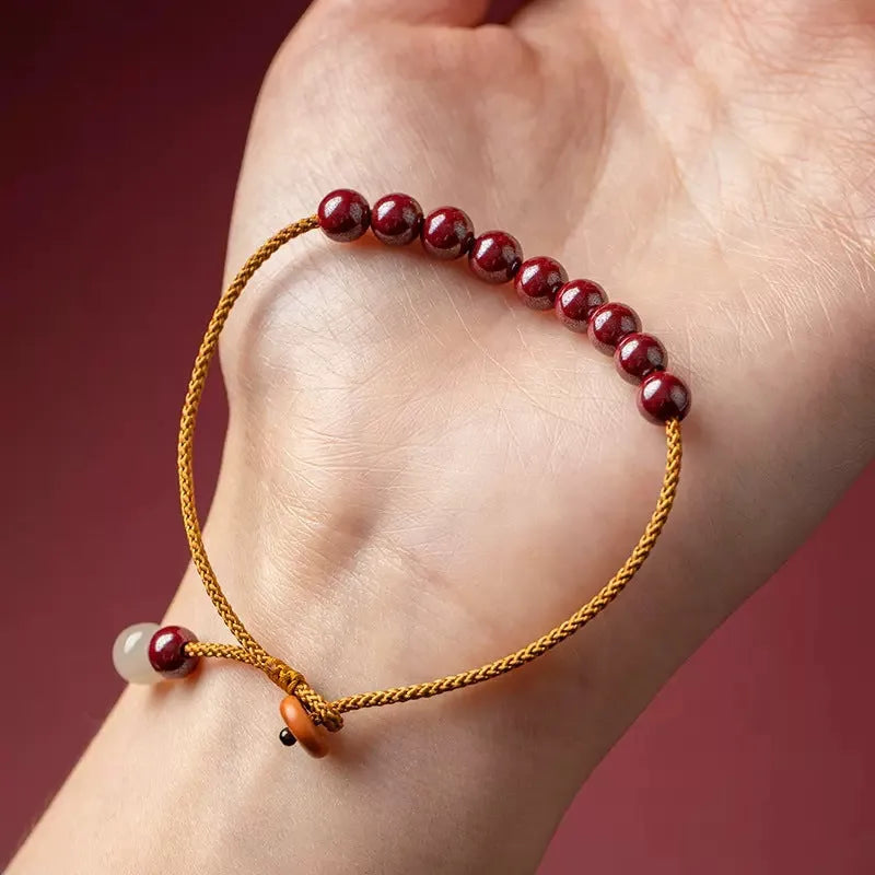 Close-up of a geometric design bracelet made from dark red cinnabar and Hetian jade on a wrist.