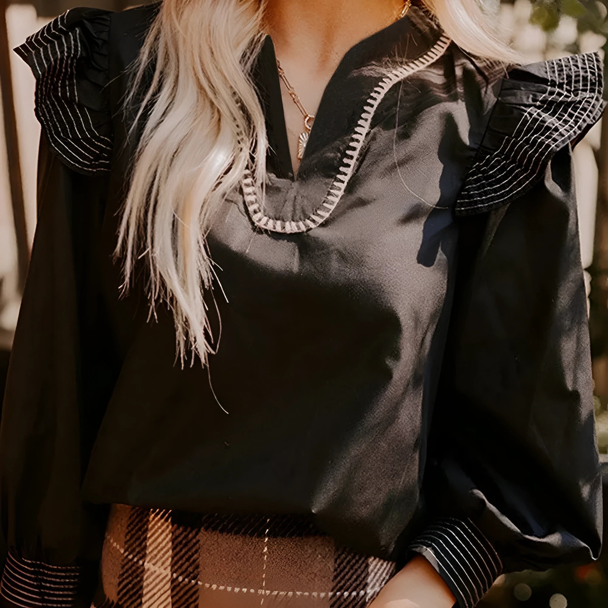 Black long sleeve V-neck blouse for women featuring ruffle details and visible contrast stitching on the seams.