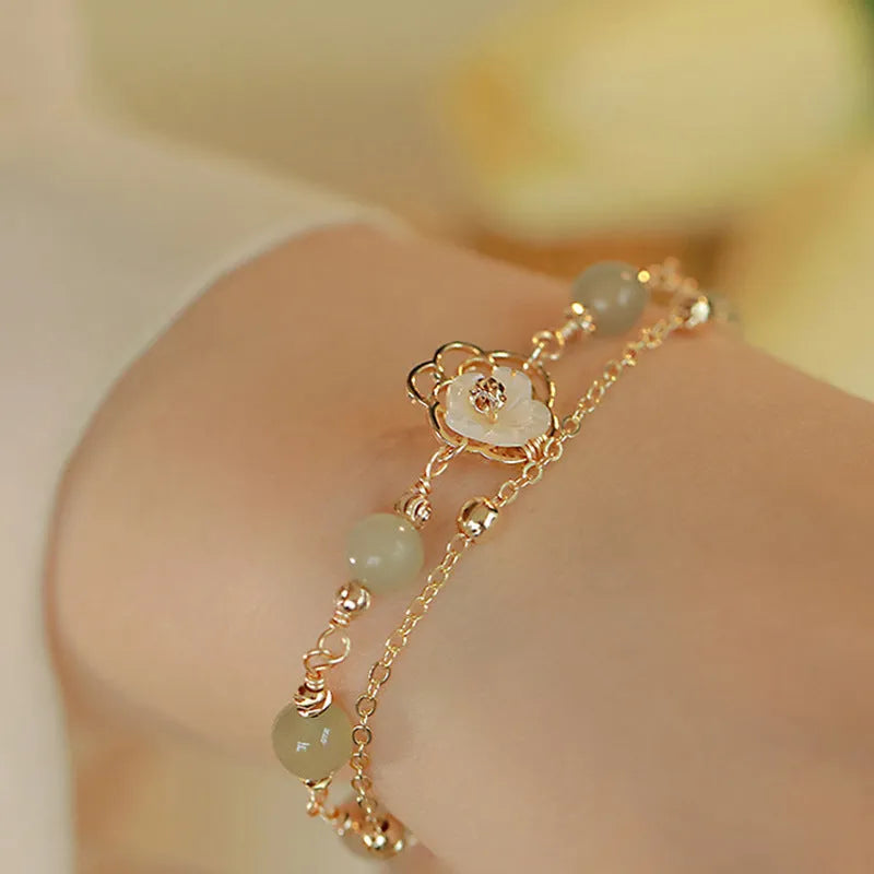Yellow gold electroplated copper bracelet with shell flower butterfly charm containing Hetian jade elements