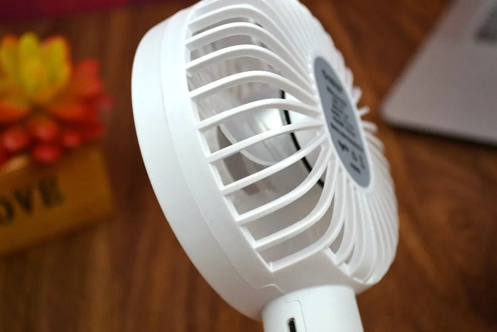 White ORICO FH1 portable USB desk fan with fine-line texture, shown as a handheld and desktop unit.
