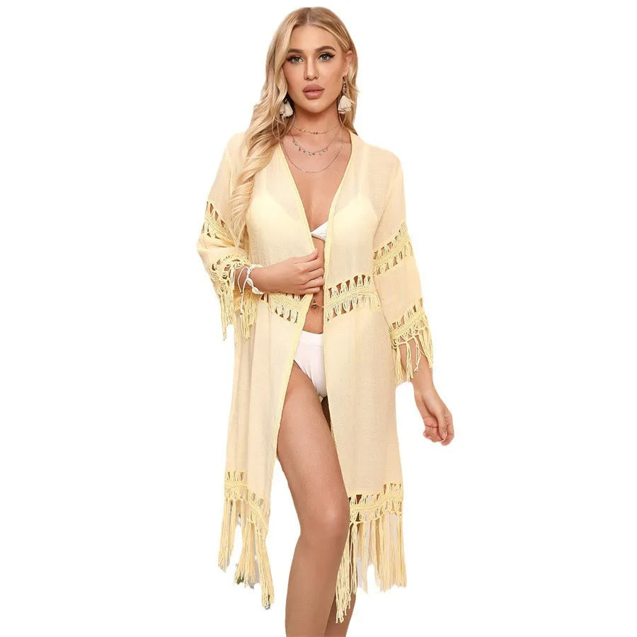 Yellow hand-crocheted acrylic cardigan with tassels, laid flat as a beach cover-up.