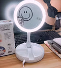 White acrylic foldable LED vanity mirror with USB charging port and double-sided design on a table