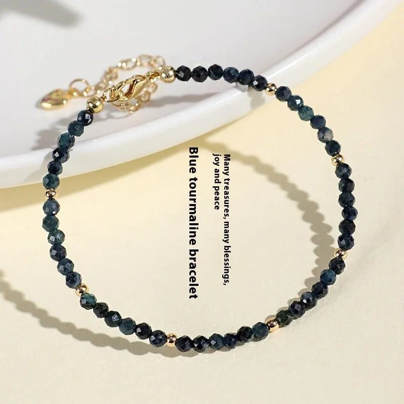 Blue tourmaline bracelet with 3mm beads and spacer beads on a wrist.