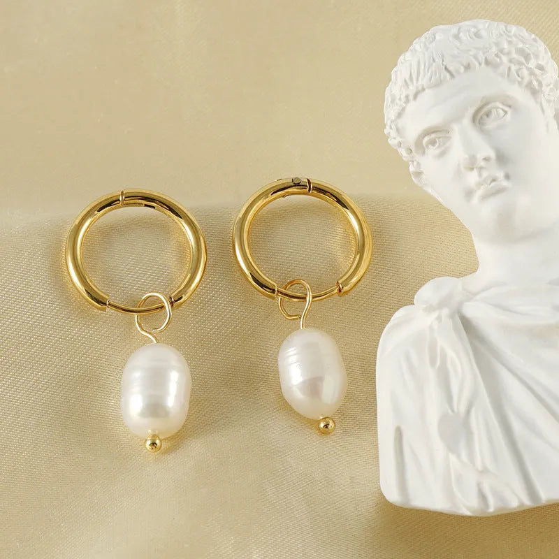 A pair of geometric drop earrings with a gold metal frame and a central freshwater pearl.