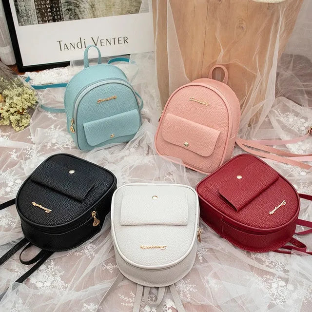 Small black PU leather women's shoulder backpack worn as a backpack, showing zipper closure and compact size.