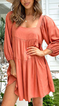 Orange backless children's dress with a square collar and puff sleeves on a mannequin.