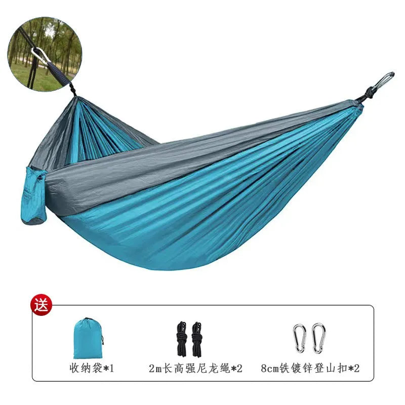 Blue nylon parachute cloth camping hammock hung between two trees.
