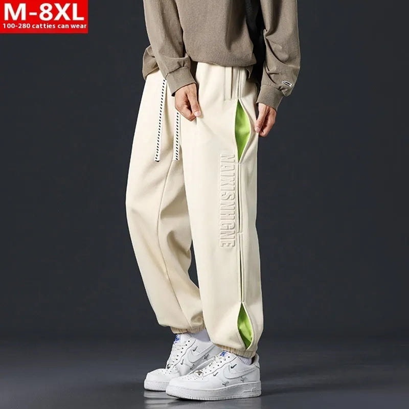 Man wearing grey green loose-fit cotton trousers with stitching print detail and an ankle band.