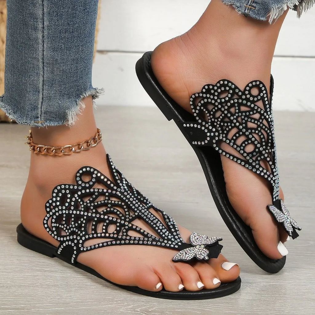 Women's black slip-on sandals with rhinestone detail and a flip-toe design on a flat rubber sole.