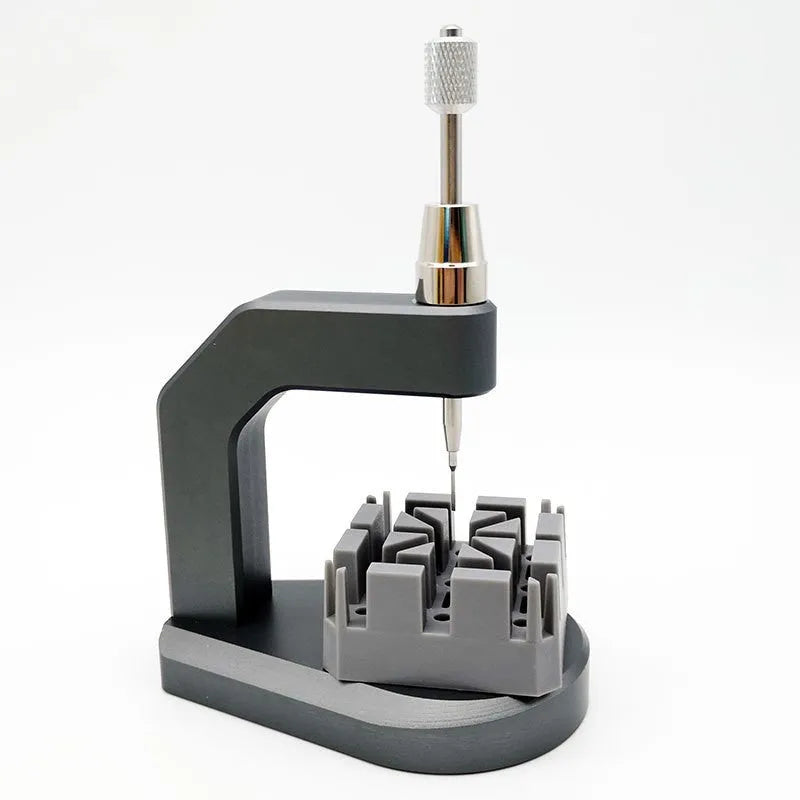 Silver-toned tool steel press strap removal tool for watches and jewellery on a plain background.