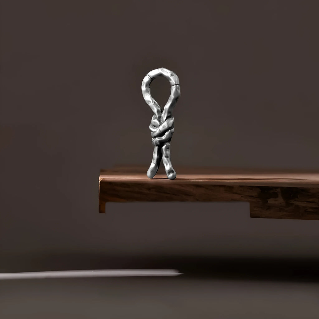 Copper bends and hitches piercing earring for auricle, showing sculptural shape and oiled finish.