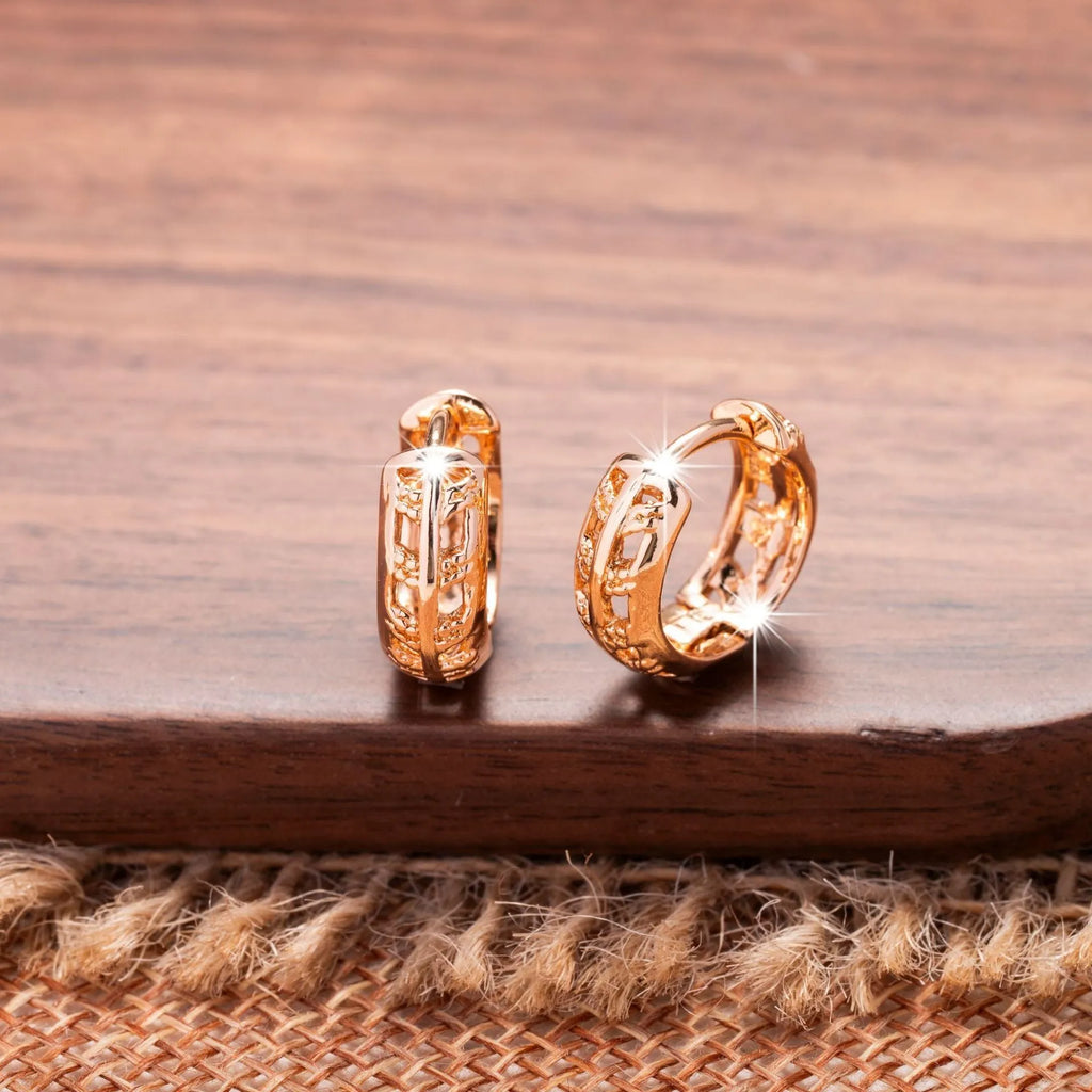 Rose gold hollowed out heart and leaf shaped copper earrings on a white background.