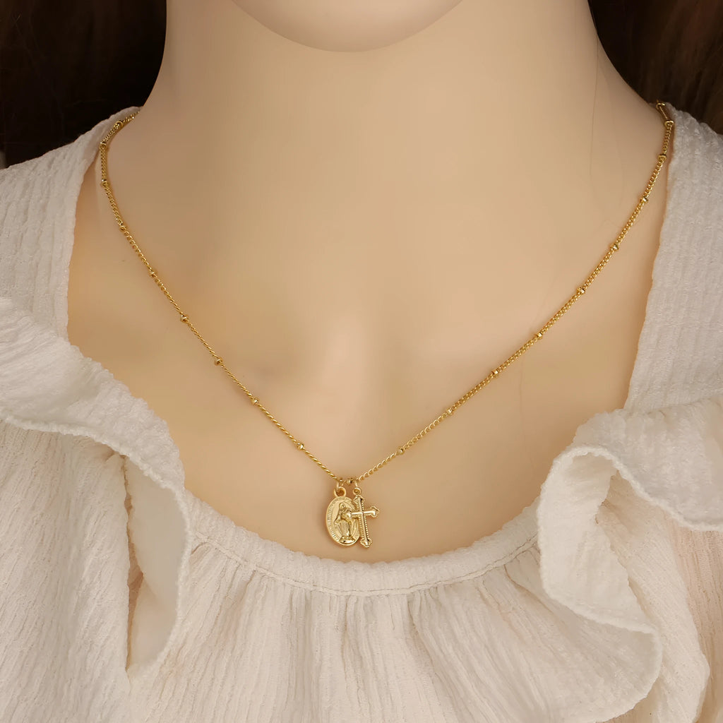 Gold coloured geometric cross Virgin Mary pendant necklace on a chain.