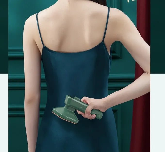 Dark green hand-held steam iron with ceramic panel showing dual temperature buttons and compact design