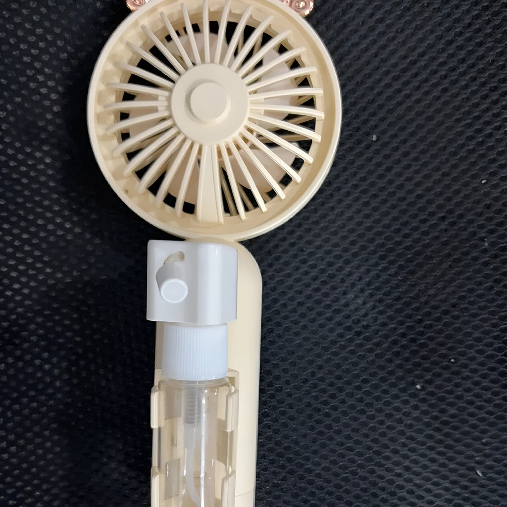 Compact plastic USB personal fan in apricot colour on a wooden desk
