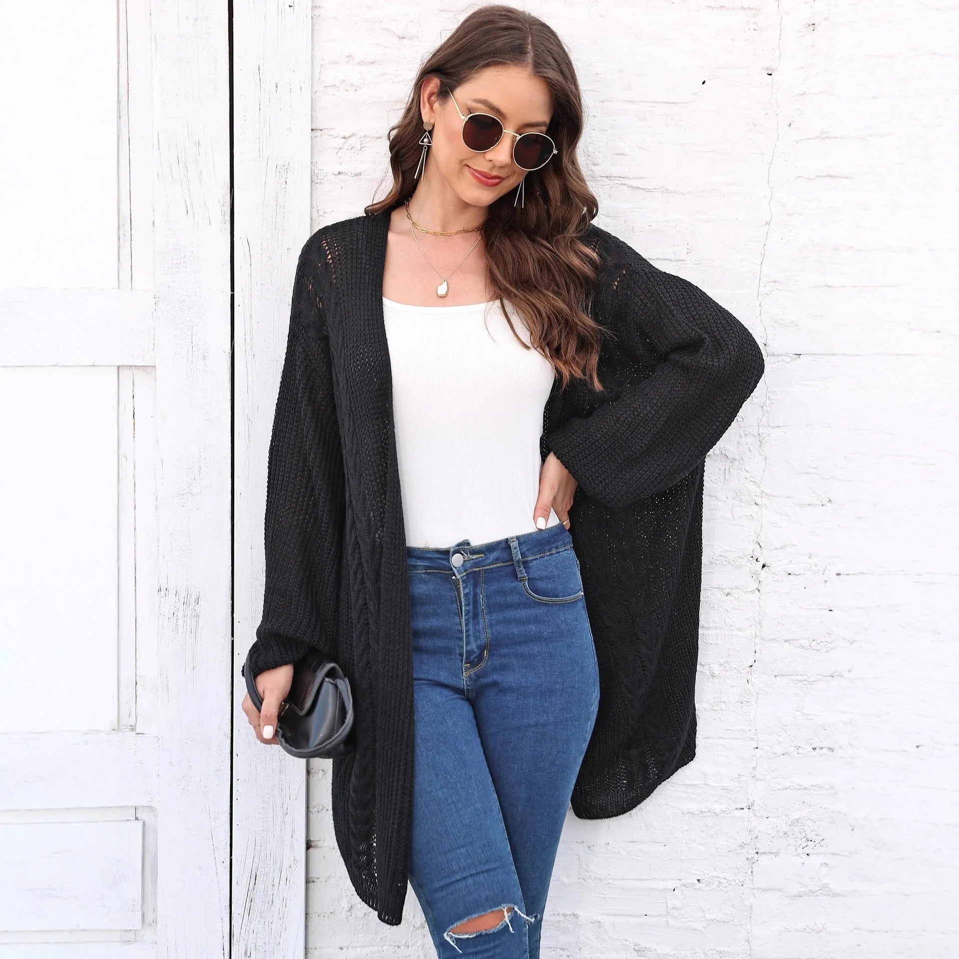 Women's loose-fitting long sleeve acrylic sweater coat in a solid colour on a hanger.