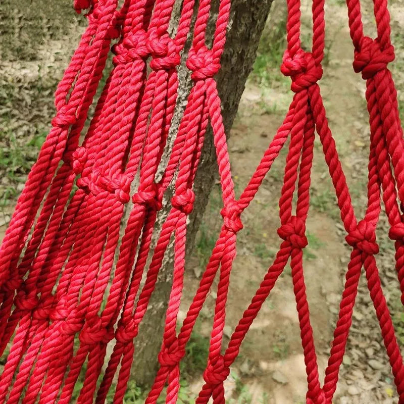Nylon rope mesh hammock hung outdoors, showing its woven design and included tying ropes.
