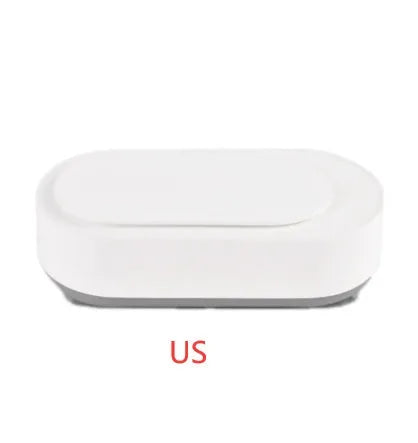 White portable ultrasonic cleaner with touch button next to jewellery and glasses on a table.