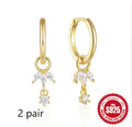 Golden coloured geometric sunflower sterling silver earrings with zircon inlay on a white background.