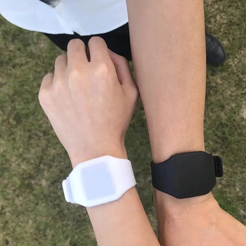 Square white electronic watch with digital display on wrist, showing touch screen and stainless steel buckle