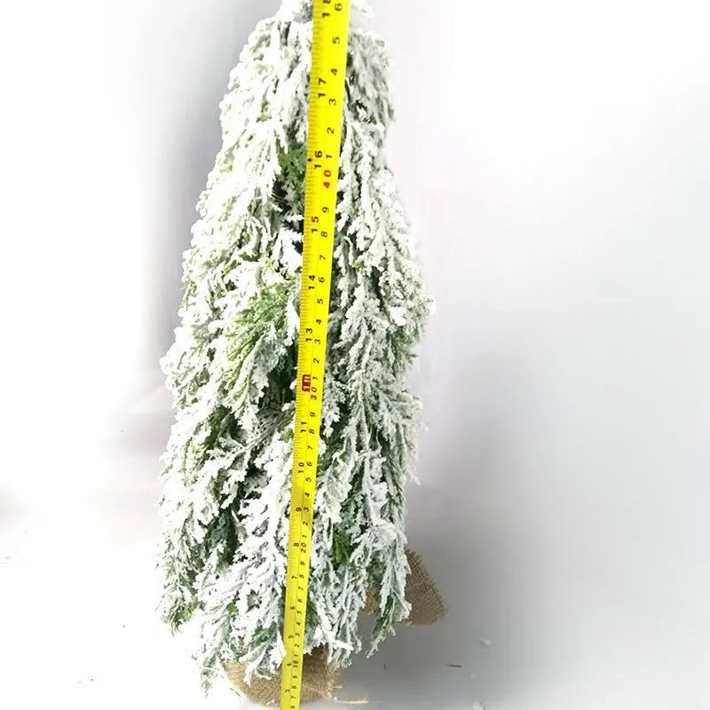 Small white 24-inch plastic Christmas tree with LED lights and simulated snow spray on desktop