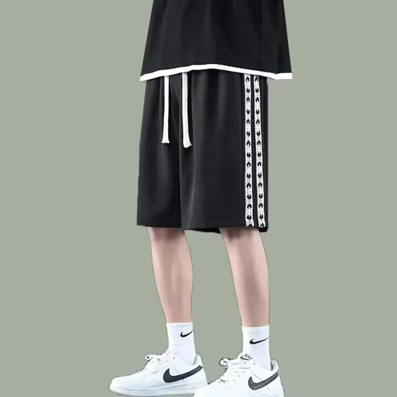 Men's black baggy track pants with elastic waistband on a neutral background.