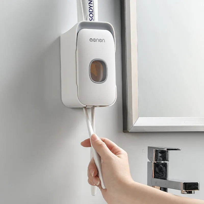 A blue automatic toothpaste dispenser mounted on a bathroom wall with a soft-touch button.