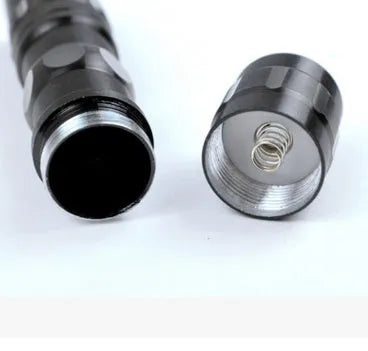 Black aluminium mini LED flashlight showing compact size next to a AA battery for scale.