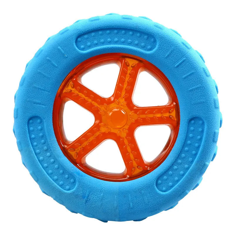 Set of three floating dog toys: a blue squeaky ball, an orange barbell, and red tyres on a beach.