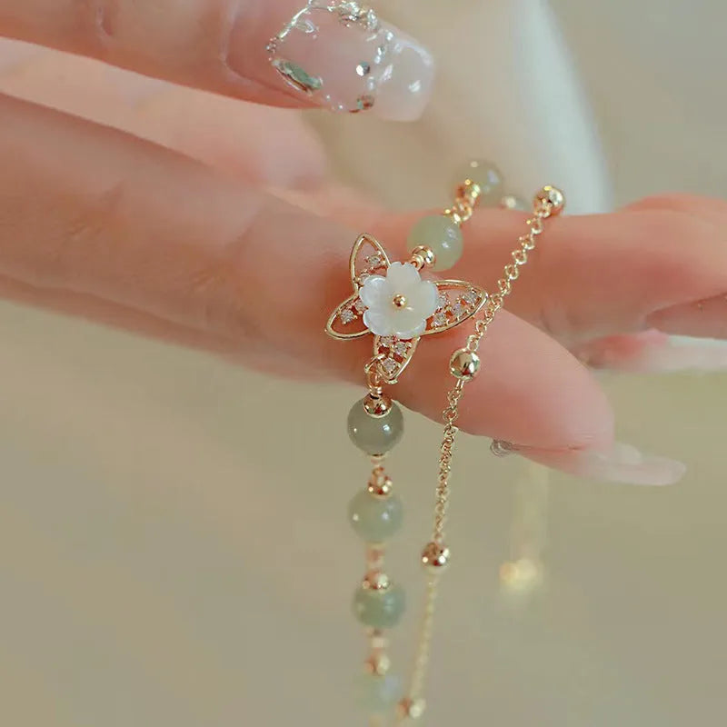 Yellow gold electroplated copper bracelet with shell flower butterfly charm containing Hetian jade elements