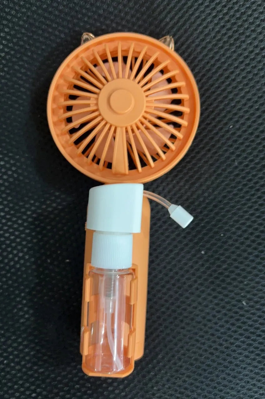 Compact plastic USB personal fan in apricot colour on a wooden desk