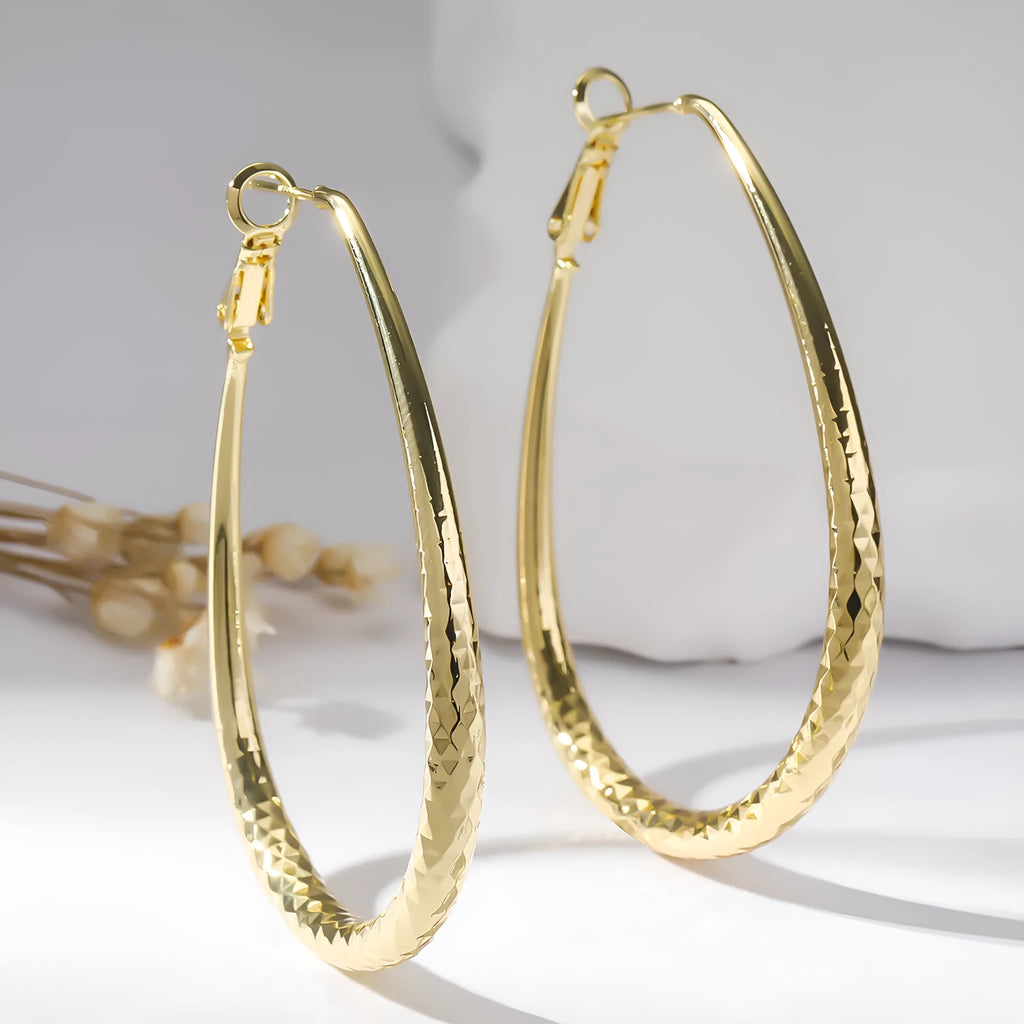Gold egg-shaped copper earrings with hypoallergenic posts and spring fasteners, unisex geometric ellipse design
