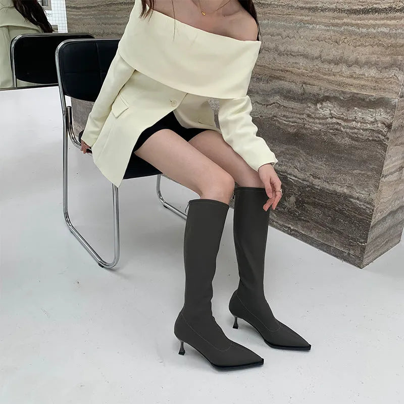 Women's black pointed-toe below-the-knee boots with a stiletto heel and a back zip fastening.