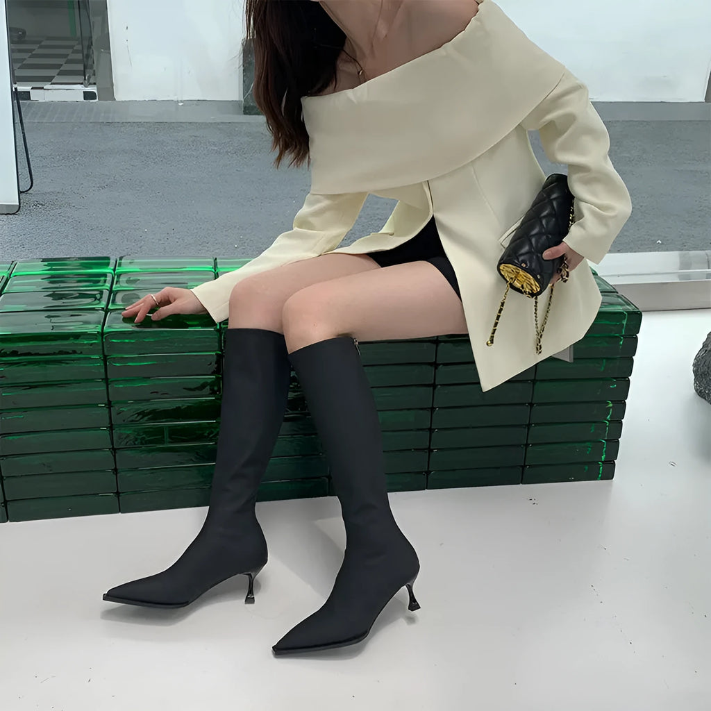 Women's black pointed-toe below-the-knee boots with a stiletto heel and a back zip fastening.