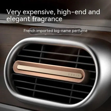Long strip car aromatherapy ornament in walnut colour, shown clipped to a car air vent.