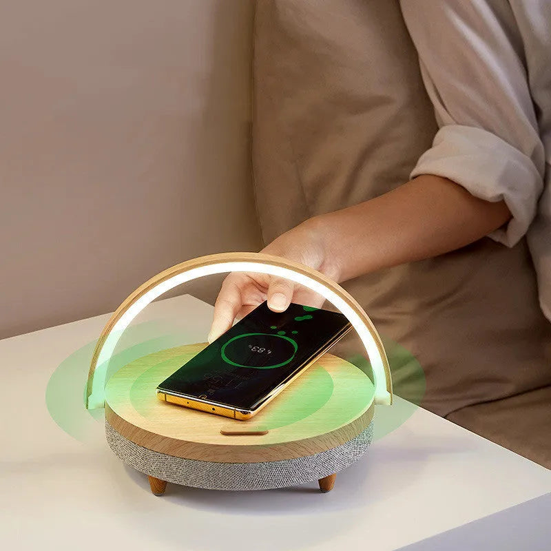 Marble pattern wireless charging desk lamp with integrated Bluetooth speaker and phone holder on a desk.