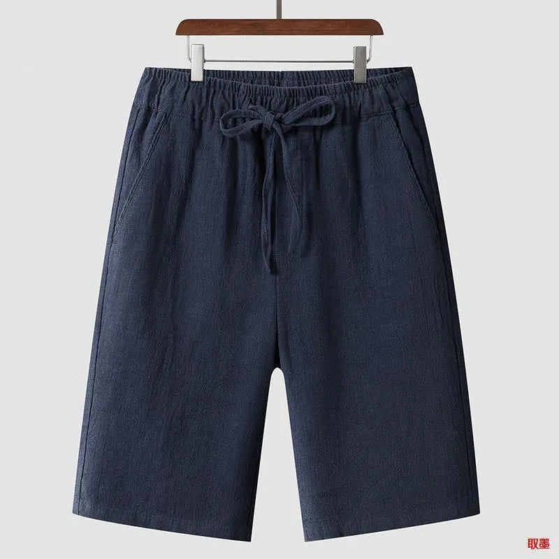 Men's beige linen shorts with a loose cropped fit and mid waistband.
